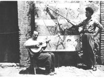 Orazio Strano (with guitar) and unidentified man in front of tableau